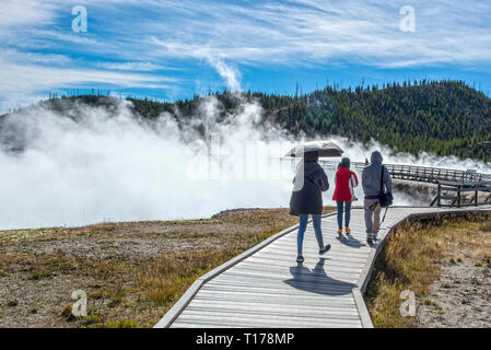 YELLOWSTONE, MONTANA USA, les touristes à pied autour du Grand Prismatic Spring dans le parc national de Yellowstone sur une promenade entourée de vapeur. Ce geyser Banque D'Images