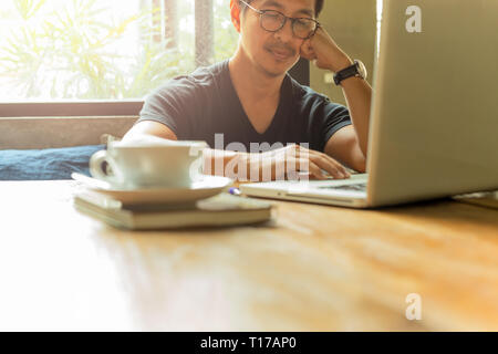 Homme sérieux travaille avec laptop while sitting in cafe avec du café sur la table Banque D'Images