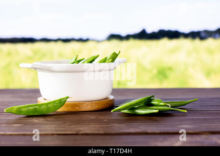 Beaucoup de pois verts entiers avec une cocotte dans un champ vert Banque D'Images