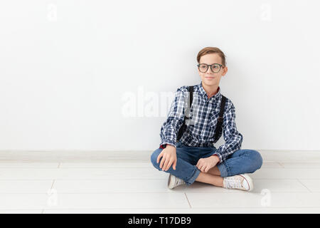 Adolescent, enfants et fashion concept - Cute child avec lunettes assis sur le marbre sur fond blanc Banque D'Images