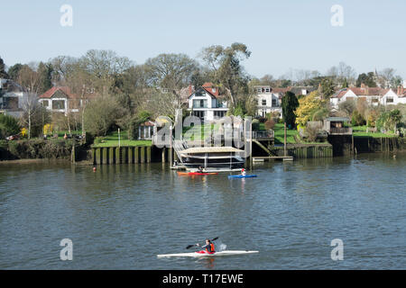 Canoéiste masculin sur la tamise à Twickenham, Middlesex, Angleterre, avec de grandes maisons de banque jusqu'à Riverside Banque D'Images