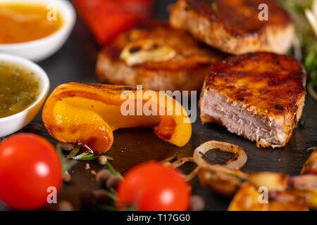Poivrons grillés avec médaillons de filet de porc, les herbes, l'ail, les trempettes et les tomates avec l'accent sur la partie de la viande en tranches par Banque D'Images
