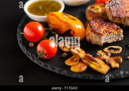 Médaillons de porc maigre grillée avec des légumes grillés servi avec sauce tomates fraîches et Banque D'Images