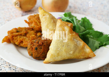 Sélection des samosas Indiens, l'oignon bhajis et pakoras garnie de feuilles de coriandre fraîche Banque D'Images