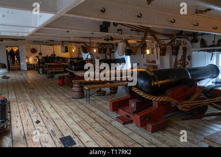 Vue générale sous le pont d'une ligne de canon sur les ponts des canons du HMS Warrior (1860), Portsmouth Historic Dockyard, UK. Banque D'Images