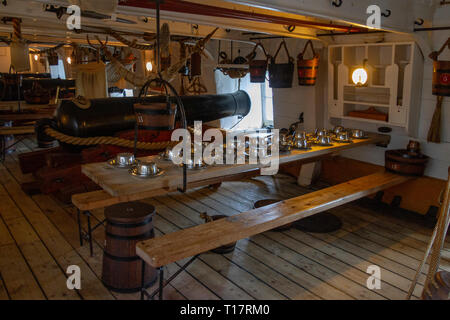 Table de salle à manger aménagé sous le pont sur le pont à canons du HMS Warrior (1860), Portsmouth Historic Dockyard, UK. Banque D'Images