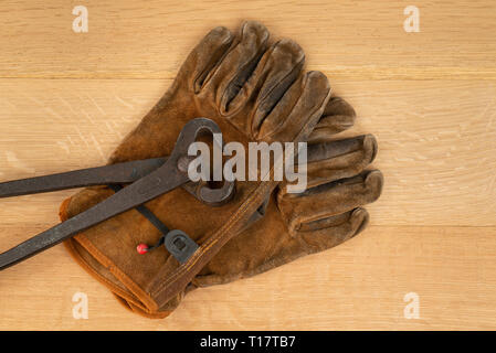 Vintage Paire de pinces coupantes poignée longue et bien porté des gants de travail en cuir fond Bois Banque D'Images