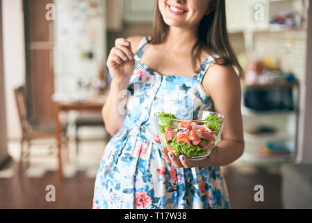 Close-up happy pregnant woman standing in kitchen, assiette de légumes et de sourire. Jeune future mère de manger des aliments sains tout en étant preg Banque D'Images