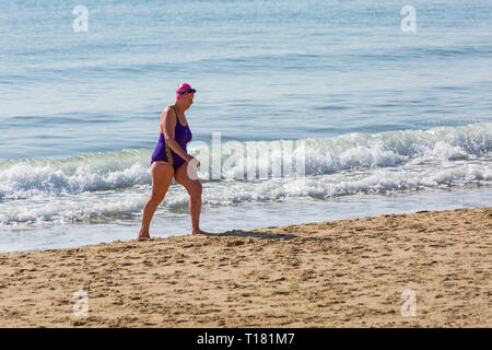 Bournemouth, Dorset, UK. 24Th Mar 2019. Météo France : belle journée ensoleillée avec un ciel bleu et soleil à plages de Bournemouth, en tant que visiteurs, chef de la station pour profiter au maximum de la météo radieuse. Senior woman walking on seashore après une baignade dans la mer. Credit : Carolyn Jenkins/Alamy Live News Banque D'Images