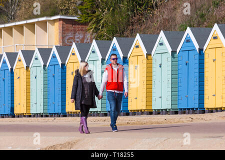 Bournemouth, Dorset, UK. 24Th Mar 2019. Météo France : belle journée ensoleillée avec un ciel bleu et soleil à plages de Bournemouth, en tant que visiteurs, chef de la station pour profiter au maximum de la météo radieuse. Couple marche main dans la main le long passé promenade cabines colorées. Credit : Carolyn Jenkins/Alamy Live News Banque D'Images