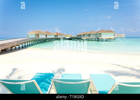 Chaises de plage Bleu sur blanc en bois avec du sable et de la jetée aux Maldives villas tropicales sur l'arrière-plan, le concept de vacances tropicales Banque D'Images