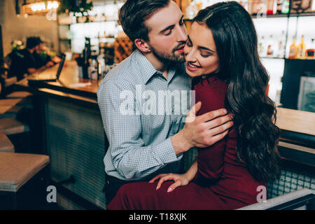 Belle photo de bel homme et belle femme assise très proches. Il tient sur ses mains et essayant ti l'embrasser. Elle sourit Banque D'Images