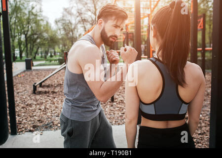 Une image de jeune homme et femme exerçant en dehors du parc. Il est montrant comment faire en boxe un bonne façon. Elle est à la recherche à c Banque D'Images