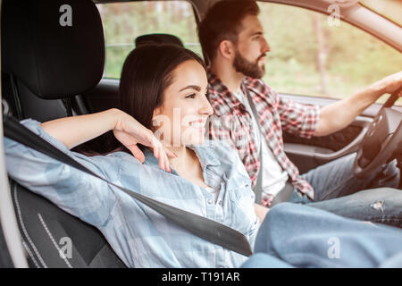 Détendu et heureux couple sont assis ensemble et équitation de voiture. Ils sont à l'aide de la ceinture de sécurité. Guy est conduite en fille est assis en dehors de lui. Elle i Banque D'Images