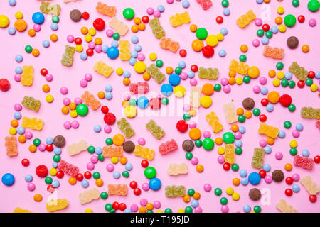 Concept d'anniversaire. Assortiment de bonbons sucrés colorés sur fond rose pastel, vue du dessus Banque D'Images