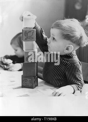 Les gens, les enfants, la lecture, la construction de la tour de cubes en plastique, daynursery «olidaritaet", Berlin, 5.2.1962, Additional-Rights Clearance-Info-Not-Available- Banque D'Images