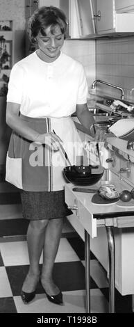 Ménage, cuisine, jeune femme au foyer de préparer une salade, 1960, les tâches ménagères, faire les travaux, housekeep, travail domestique, ménage, demi-longueur, demi-longueur, debout, un tablier, des tabliers, des sourires, sourire, sourire, tenir, tenir, salade, saladier, saladiers, bols, bol, mélanger, mélanger, table, tables, cuisine, cuisines, Cuisine, Placards, placard mural, cuisinière, four, cuisine, cuisinière, évier de cuisine, les éviers de cuisine, ménage, ménage, cuisine, cuisson, cuire, la cuisson, femme au foyer, femmes au foyer, femme au foyer, la préparation, la préparation, l'Additional-Rights Clearance-Info, salade--Not-Available Banque D'Images