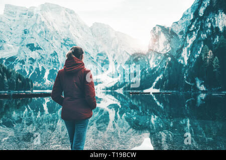 Woman in red jacket est debout sur la côte du lac Braies au lever du soleil en automne. Dolomites, Italie. Paysage avec fille, célèbre lac avec de belles re Banque D'Images