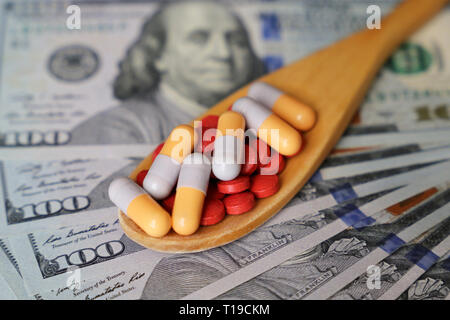 Comprimés et gélules dans cuillère en bois sur le dollar US. Concept de soins de santé, secteur pharmaceutique, le prix des médicaments, de pharmacie, de médecine et de l'économie Banque D'Images