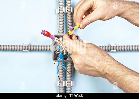 L'enregistrement est électricien les extrémités des fils dans le tube thermorétractable au cours de l'installation de la boîte de jonction. Banque D'Images