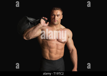 Bodybuilder forte avec Six Pack sur noir sur fond noir Banque D'Images