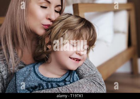 Les baisers de la mère est son fils. Mère et fils. Heureuse fête des mères. Mother hugging son enfant à la maison Banque D'Images