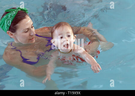 Véritable jeune mère apprenant avec sa petite fille à nager dans la piscine où la confiance et un lien est formé pour la vie Banque D'Images