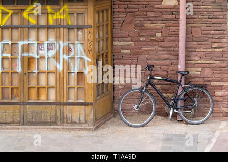 Un vélo enchaîné à une gouttière, à côté d'une porte l'objet de vandalisme, graffiti à Barcelone Espagne Banque D'Images