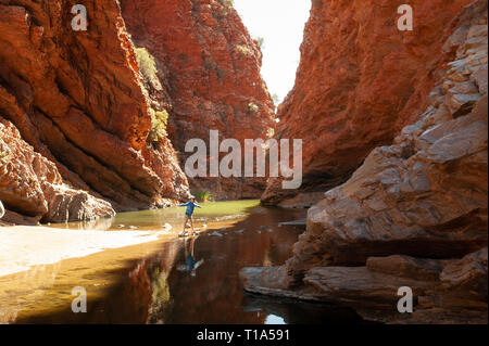 Un jeune garçon joue sur le stepping stones dans les bas-fonds de Simpsons Gap, Territoire du Nord, Australie Banque D'Images