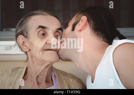 Jeune homme embrassant la joue de sa grand-mère, montrant son amour, respect et gratitude. Banque D'Images