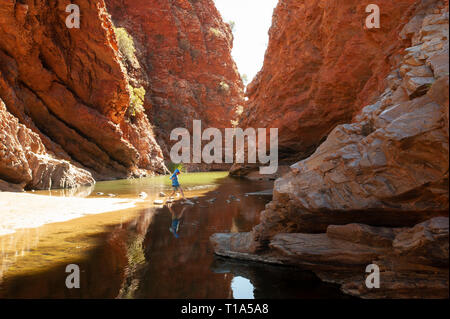 Un jeune garçon joue sur le stepping stones dans les bas-fonds de Simpsons Gap, Territoire du Nord, Australie Banque D'Images