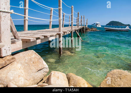 Paysage pittoresque de romantique, pont en bois par la mer. Avis de pierre côte, bateau à voile à louer à crystal, mer turquoise avec islan Banque D'Images