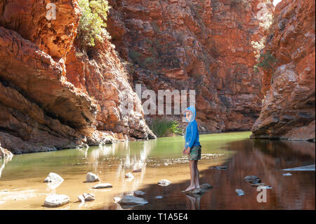 Un jeune garçon joue sur le stepping stones dans les bas-fonds de Simpsons Gap, Territoire du Nord, Australie Banque D'Images