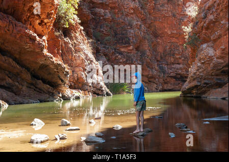 Un jeune garçon joue sur le stepping stones dans les bas-fonds de Simpsons Gap, Territoire du Nord, Australie Banque D'Images