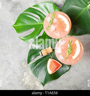 Le romarin et pamplemousse boisson glace dans deux gobelets en verre élégante sur fond de béton gris. Vue de dessus du châssis carré Banque D'Images
