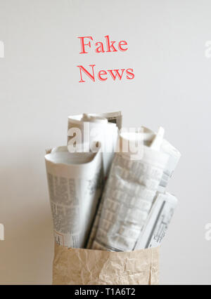 Fake news concept - mots rouges 'Fausse News' sur le dessus de sac de papier rempli de journaux Banque D'Images