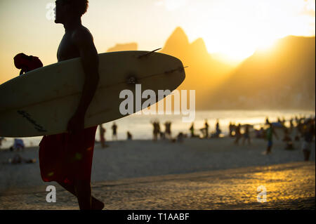 RIO DE JANEIRO - Mars 20, 2017 : un jeune surfeur brésilien promenades sur la promenade de l'Arpoador, surf populaire point et donnent sur le coucher du soleil. Banque D'Images