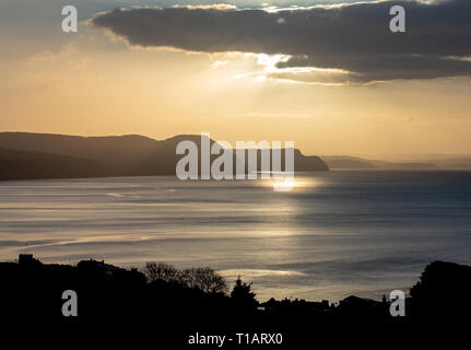 Lyme Regis, dans le Dorset, UK. Mar 25, 2019. Météo France : plus de lumière étrange Golden Cap sur la côte jurassique comme le soleil se brise par l'intermédiaire d'une banque de cloud. Vue de Lyme Regis. Credit : PQ Images/Alamy Live News Banque D'Images