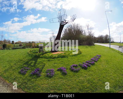 Eastchurch, Kent, UK. 25 mars, 2019. Météo France : une journée ensoleillée dans le village d'Eastchurch, Kent. Sur la photo : fleurs entourent la sculpture aviation énonçant 'Eastchurch'. La sculpture a été mis en place pour célébrer le centenaire de la fondation de l'aviation britannique sur l'île de Sheppey 1909-2009. Credit : James Bell/Alamy Live News Banque D'Images