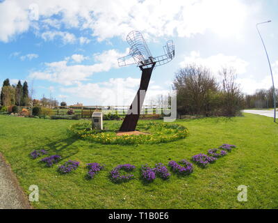 Eastchurch, Kent, UK. 25 mars, 2019. Météo France : une journée ensoleillée dans le village d'Eastchurch, Kent. Sur la photo : fleurs entourent la sculpture aviation énonçant 'Eastchurch'. La sculpture a été mis en place pour célébrer le centenaire de la fondation de l'aviation britannique sur l'île de Sheppey 1909-2009. Credit : James Bell/Alamy Live News Banque D'Images