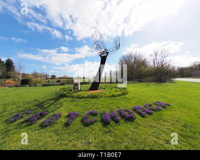 Eastchurch, Kent, UK. 25 mars, 2019. Météo France : une journée ensoleillée dans le village d'Eastchurch, Kent. Sur la photo : fleurs entourent la sculpture aviation énonçant 'Eastchurch'. La sculpture a été mis en place pour célébrer le centenaire de la fondation de l'aviation britannique sur l'île de Sheppey 1909-2009. Credit : James Bell/Alamy Live News Banque D'Images