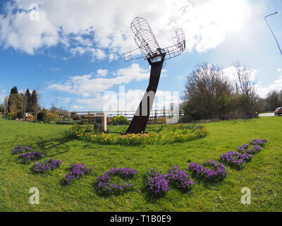 Eastchurch, Kent, UK. 25 mars, 2019. Météo France : une journée ensoleillée dans le village d'Eastchurch, Kent. Sur la photo : fleurs entourent la sculpture aviation énonçant 'Eastchurch'. La sculpture a été mis en place pour célébrer le centenaire de la fondation de l'aviation britannique sur l'île de Sheppey 1909-2009. Credit : James Bell/Alamy Live News Banque D'Images