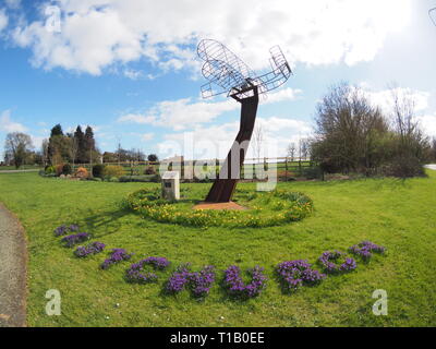 Eastchurch, Kent, UK. 25 mars, 2019. Météo France : une journée ensoleillée dans le village d'Eastchurch, Kent. Sur la photo : fleurs entourent la sculpture aviation énonçant 'Eastchurch'. La sculpture a été mis en place pour célébrer le centenaire de la fondation de l'aviation britannique sur l'île de Sheppey 1909-2009. Credit : James Bell/Alamy Live News Banque D'Images