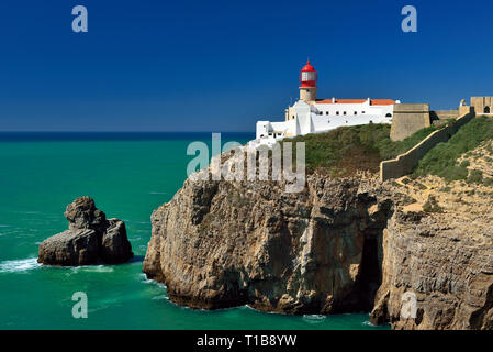 Vue latérale du phare rouge avec blanc, en s'appuyant sur des falaises rocheuses avec Blue Horizon et green ocean Banque D'Images