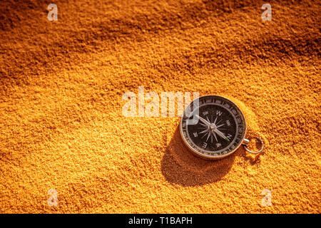 Détail d'un compas en métal reposant sur le sable du désert de dunes. Concept de voyage et le désir de l'aventure. Banque D'Images