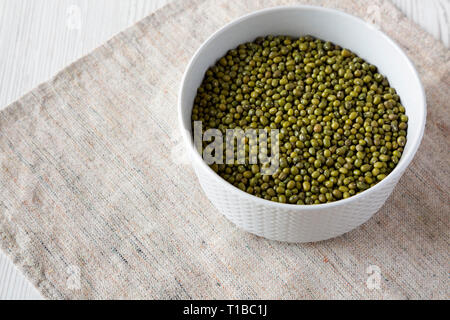 Les haricots mungo vert cru dans un bol en bois blanc, gris sur la surface, low angle view. Banque D'Images