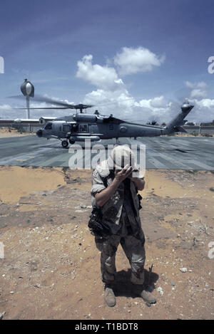 29 octobre 1993 un soldat de l'armée américaine tourne le dos à la tempête comme un Sikorsky SH-60 de l'US Navy hélicoptère Seahawk de l'USS Abraham Lincoln décolle de l'hélisurface au QG de l'ONUSOM à Mogadishu, en Somalie. Banque D'Images