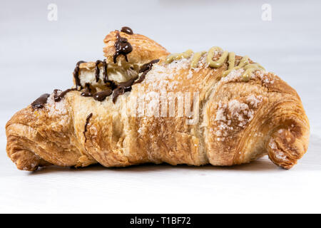 Brioche gourmande avec du chocolat et farci à la pistache sur une table en bois Banque D'Images