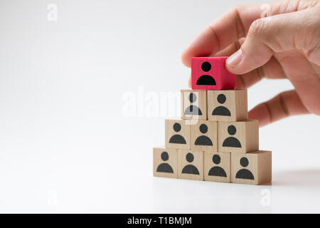 Mettre la main sur le dessus du bloc cube en bois pyramide pour concept de leadership Banque D'Images