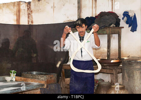 Jeune Ouïghour qui fait des nouilles tirées à la main, marché du dimanche de Kashgar, Kashgar, région autonome du Xinjiang, Chine. Banque D'Images